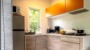 A kitchen with a built-in microwave, a window, a stove, and a coffee maker. - ZEcamping 3 étoiles mobil-home TV LV BBQ 27m2 4 pers (Pordic)