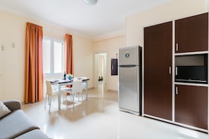 Eine moderne Küche mit einem Kühlschrank, einem Esstisch mit Stühlen und einer Couch.
