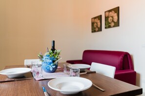 Ein Esstisch mit Tellern, Gläsern, Besteck und einer Vase mit Blumen.