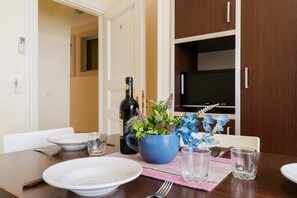 A dining table set with plates, glasses, a bottle, and a decorative plant.