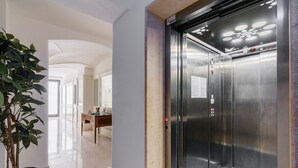 An elevator with a control panel, a potted plant, and a hallway with a wooden table and chairs. - Apartment in A Hotel 'Unit 1' with Wi-Fi (Gallipoli)