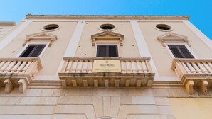 A building facade with three arched windows and a plaque reading 'Palazzo Mongio.' - Apartment in A Hotel 'Unit 1' with Wi-Fi (Gallipoli)