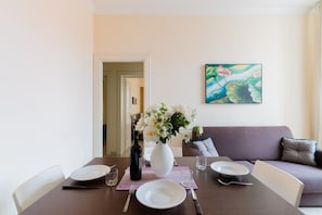 Une table à manger avec des assiettes, des couverts, un vase de fleurs et une bouteille.
