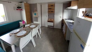 Una cocina compacta con comedor, muebles blancos y estufa integrada.