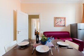 Une table à manger dressée avec des assiettes, des couverts, une bouteille et un vase rempli de fleurs.