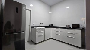 Una cocina moderna con armarios blancos, un refrigerador negro y un microondas.