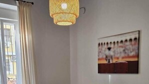 Una sala de estar con un sofá amarillo, una mesa de centro de madera, una silla roja y un tapete estampado.