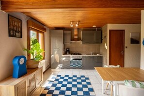 A compact kitchen with modern appliances, a checkered floor mat, and a wooden ceiling. - ZEcamping 4* animé piscine couverte animaux acceptés locatif TV LV (Granges-sur-Vologne)