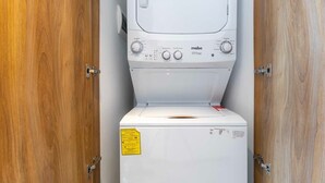 A white washing machine in a wooden cabinet with a yellow warning label. - Michoacan Space Lovely Apartment With Balcony (Mexico City)