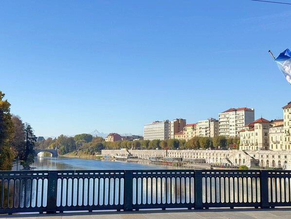 A river with a bridge, buildings with classical architecture, and a flag. - Loft Portici in Torino (Turin)