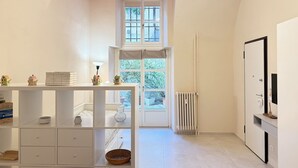 A bright, modern room with a white color scheme, a red ceiling, a large window, a radiator, and a white cabinet with a mirror. - Loft Portici in Torino (Turin)