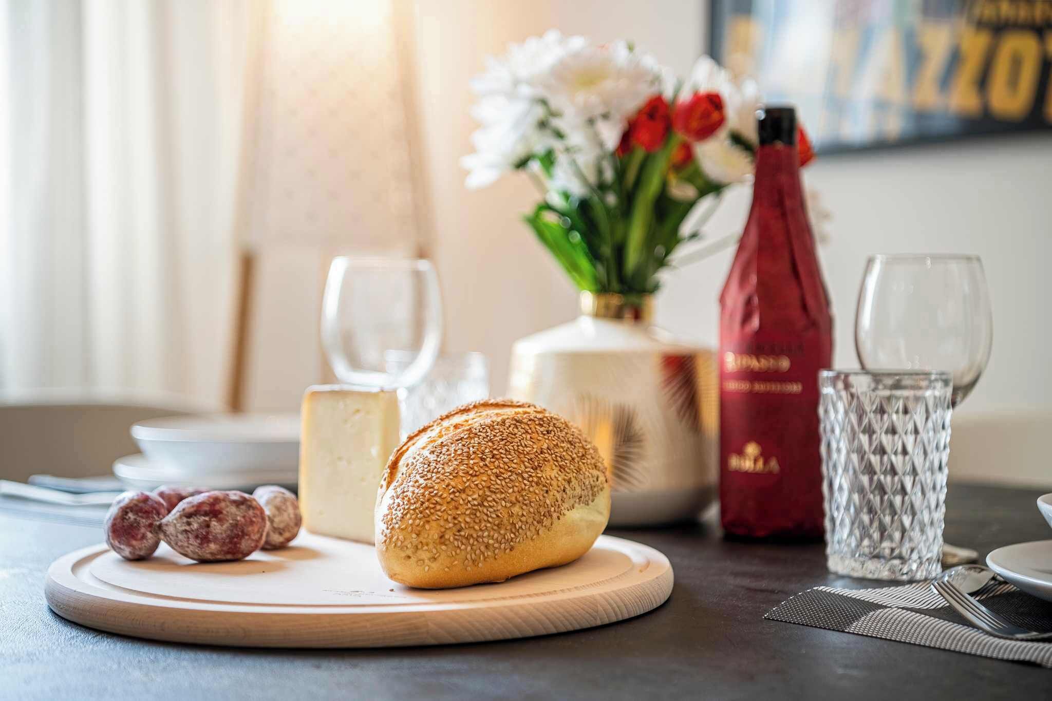 Une table avec un plateau rond en bois, une miche de pain, une bouteille et un verre.