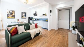 A modern living room with a green sofa, a small dining table, and a kitchen area in the background. - Casa Belfiore in Firenze (Florence)