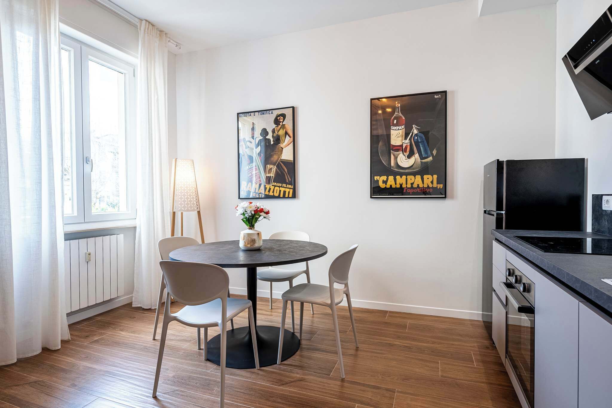 Een moderne keuken met een eethoek, met een ronde tafel en vier stoelen, een zwart aanrecht en een ingebouwde oven.
