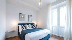 A bedroom with a bed, a nightstand, a wall-mounted light, and a window with curtains. - Casa Belfiore in Firenze (Florence)