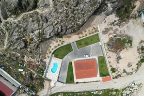 Vista aérea de una propiedad con piscina, cancha de tenis y zona de estacionamiento.