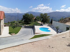 Ein Wohnhaus mit Pool, befestigter Auffahrt und Blick auf ferne Berge.