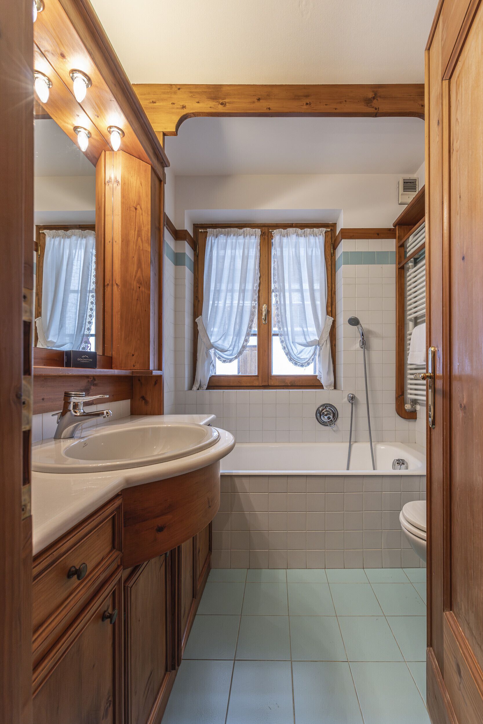 Een badkamer met houten kastjes, een wastafel, een bad en een douche.