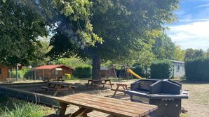 Zona de picnic amb taules de fusta i una barbacoa.