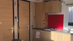 A compact room with a bed, a kitchenette, and a door labeled "Tibbetts Room". - ZEcamping 2* chiens acceptés locatif TV clim 20m2 2 pers (Angicourt)