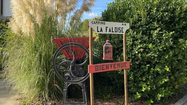 Segnaletica con su scritto 'CAMPING LA FALOISE' e 'BIENVENUE', indica un'area campeggio.