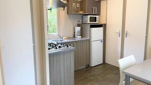 Eine kleine Küche mit Gaskochfeld, Mikrowelle, Kaffeemaschine und Kühlschrank.