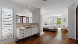 Un baño moderno con un espejo grande, un lavabo sobre encimera y un mueble de tocador de madera.