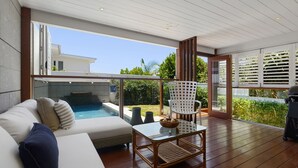 Un espacio exterior moderno con piscina, sofá y mesa.