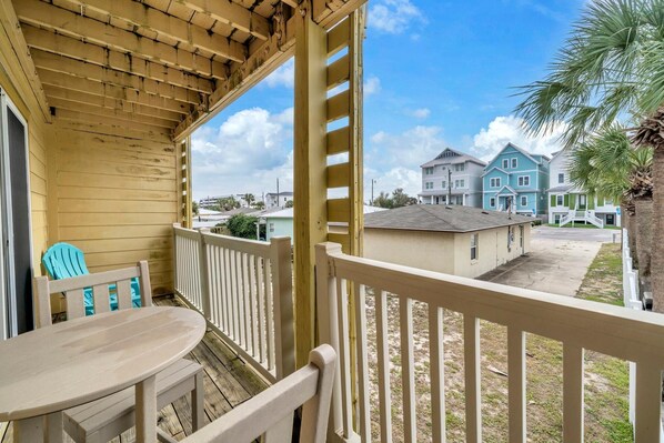 A wooden deck with a table and chairs, overlooking a residential area with houses and a clear sky. - Surfwinds #3 (Panama City Beach)