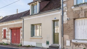 A two-story building with a green door, a red door, and a window with shutters. - Gîte à l'aube – 3 bedrooms (Saint-Aignan)