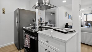 Une cuisine moderne dotée d’un réfrigérateur en acier inoxydable, d’un four encastré et d’un plan de travail en marbre blanc.