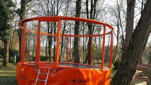 Ett orange utomhusområde med en stege, omgivet av träd.