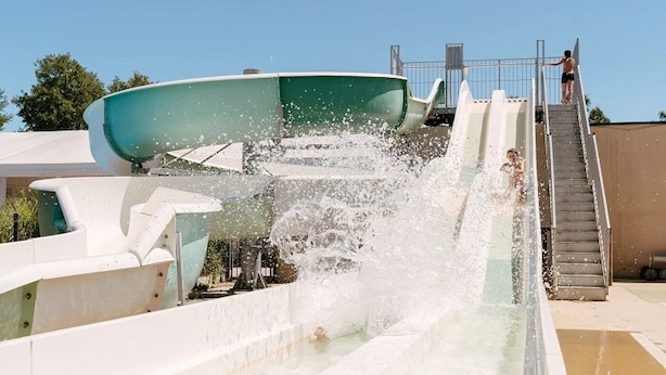 Un toboggan aquatique avec une personne en haut et une autre en bas.