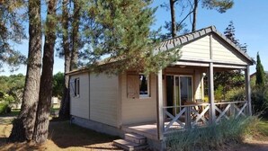 Une petite cabane en bois, d’un seul étage, dotée d’un porche et entourée de grands pins.