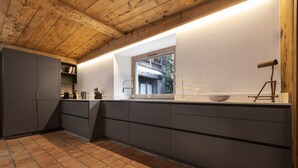 Une cuisine moderne avec des meubles de couleur sombre, une fenêtre et un plafond en bois.