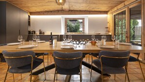 Un coin repas avec une table en bois dressée pour quatre personnes, entourée de chaises à l’assise rembourrée de couleur sombre, dotées de pieds dorés.