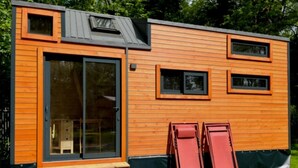 A modern wooden cabin with large sliding glass doors, a small porch, and a sloped roof. - ZEcamping 3 étoiles animaux acceptés locatif BBQ clim 4 pers (Neuilly-sur-Marne)