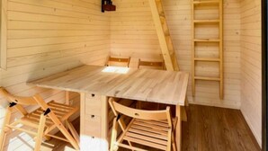 A wooden interior with a dining table and chairs, a ladder, and a small shelf. - ZEcamping 3 étoiles animaux acceptés locatif BBQ clim 4 pers (Neuilly-sur-Marne)