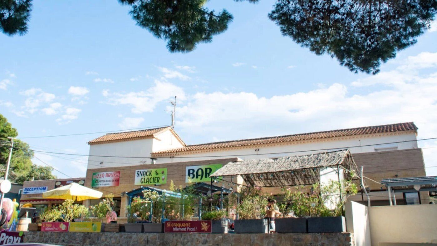 A building with multiple signs for a pizza place, a snack bar, and a bar.