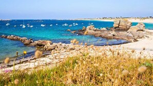 Eine Küstenlandschaft mit klarem, blauem Wasser, Felsformationen und einem Sandstrand.