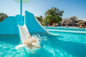 Une piscine avec un toboggan et des chaises longues.