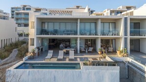 A modern multi-story hotel with a swimming pool, outdoor seating, and balconies. - Cabo Costa - Private Infinity Pool and Ocean View (Cabo San Lucas)