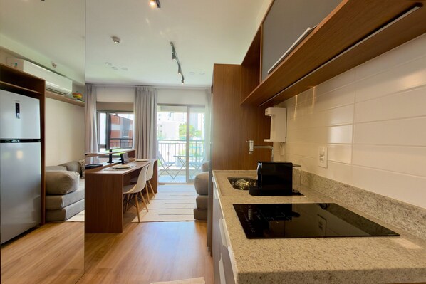 Una cucina moderna con piano cottura integrato, un'area pranzo con tavolo e sedie, e vista verso il balcone.