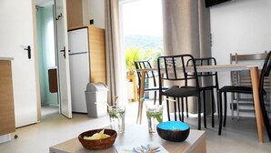 Et moderne køkken med spiseplads, inklusiv et bord med stole, et køleskab og en skraldespand.