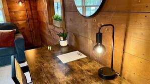 Un interior de madera con un espejo redondo, una mesa con una lámpara y un sofá.