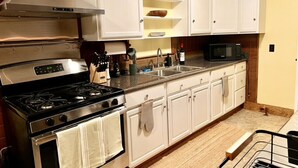 Una cocina con armarios blancos, una estufa de acero inoxidable, un microondas y un lavamanos.