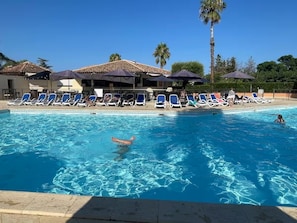 A swimming pool with lounge chairs and umbrellas, surrounded by buildings with tiled roofs. - T3 sea view for 4 people, walking distance to beach, swimming pool (Linguizzetta)