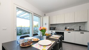 Eine moderne Küche mit weißen Schränken, einer schwarzen Arbeitsplatte und einem großen Fenster.