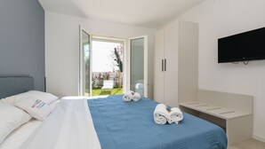 Ein modernes Hotelzimmer mit Bett, Wandfernseher und einer Schiebetür zu einem Balkon.