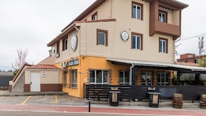 A two-story building with a flat roof, a sign reading 'Festa Sona,' and a small outdoor seating area with benches and barrels. - Habitación Doble 24 en Somo: Confort y Balcón Privado (Somo)